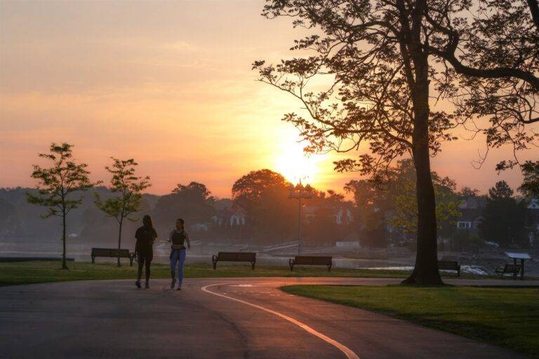 Twee mensen wandelen samen over een pad in een park bij zonsopgang